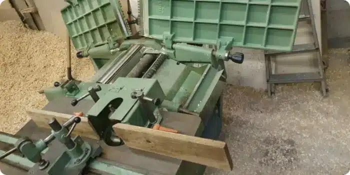 Mécanique ouverte d'une raboteuse dégauchisseuse d'occasion : chaîne d'entraînement, courroie, pignons et moteur