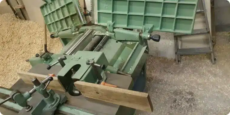 Mécanique ouverte d'une raboteuse dégauchisseuse d'occasion : chaîne d'entraînement, courroie, pignons et moteur